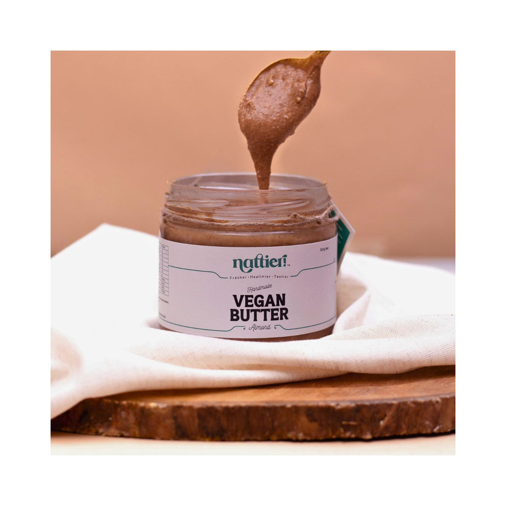 Jar of vegan butter with a spoonful being lifted, on a brown white background