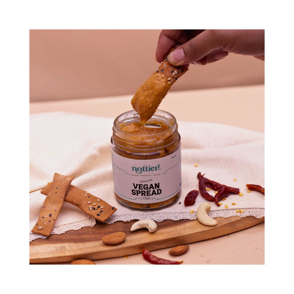 Persons hand dipping cracker in jar with with brown and white background