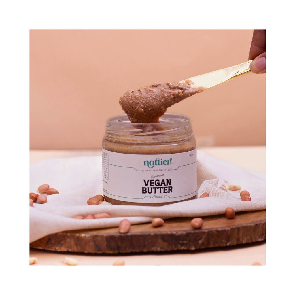 Jar of vegan butter with a spoonful being lifted, on a beige background