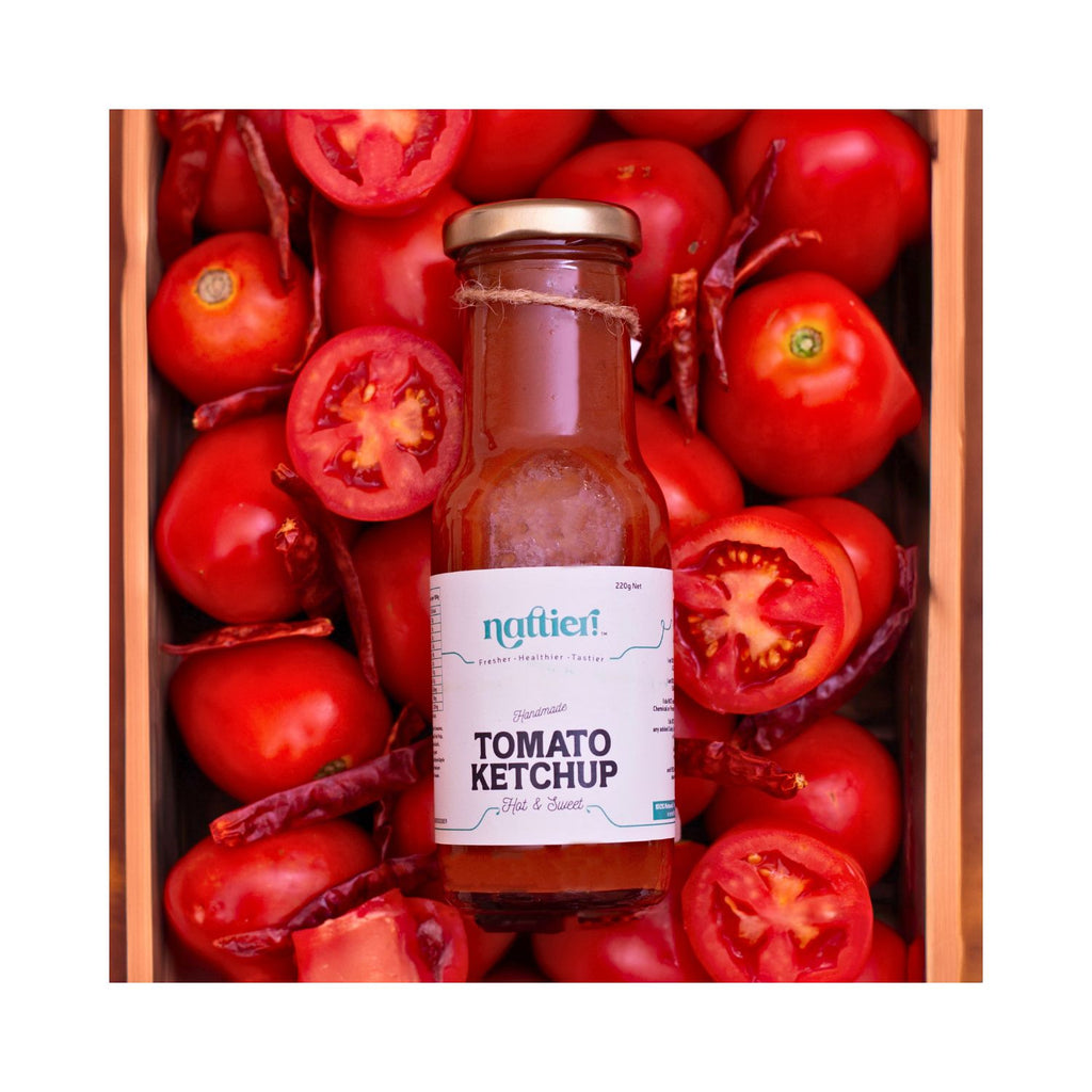 Bottle of hot & sweet ketchup with a white label in a wooden crate of red tomatoes