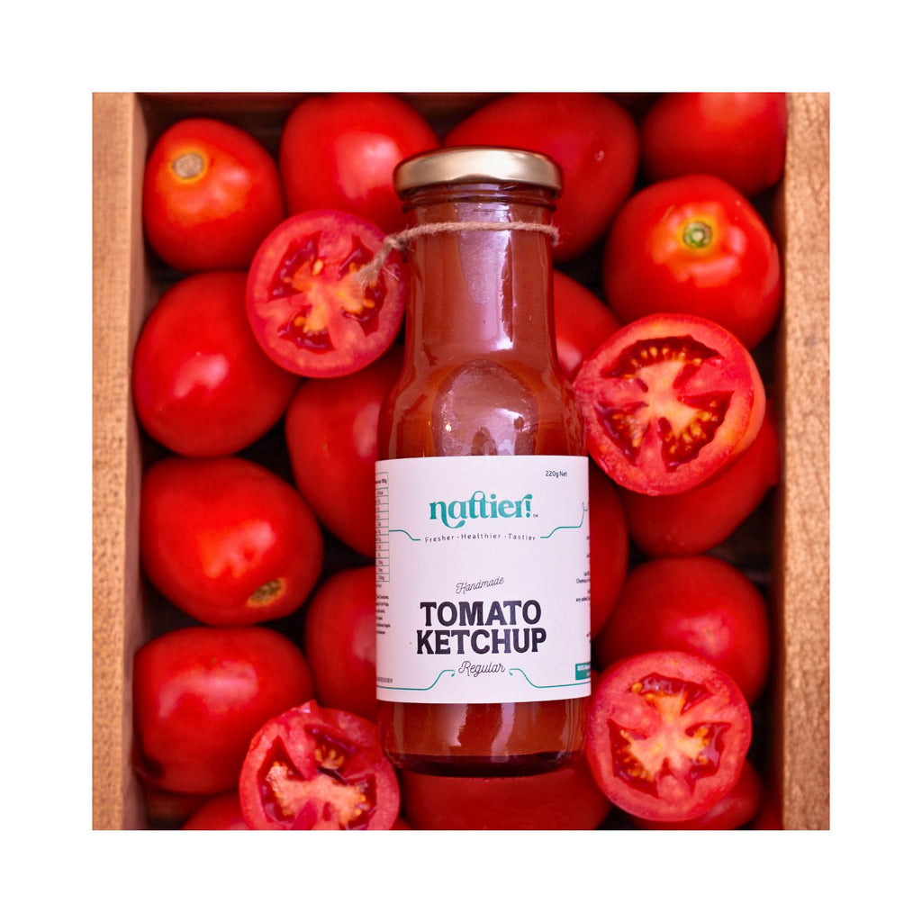 Bottle of Nattier Tomato Ketchup surrounded by fresh tomatoes in a wooden box.