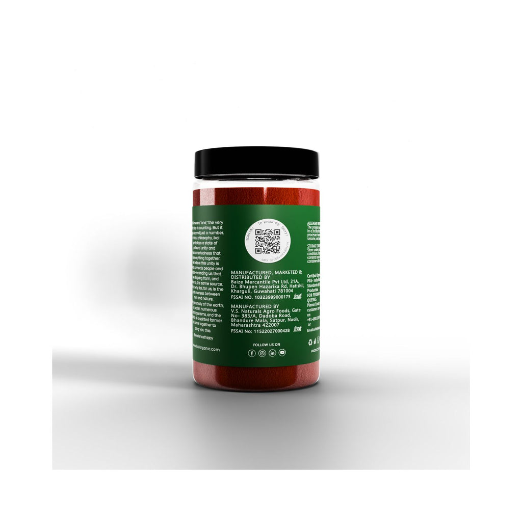 Jar of Ikai red chilli powder with green label about manufacturing info on a white background
